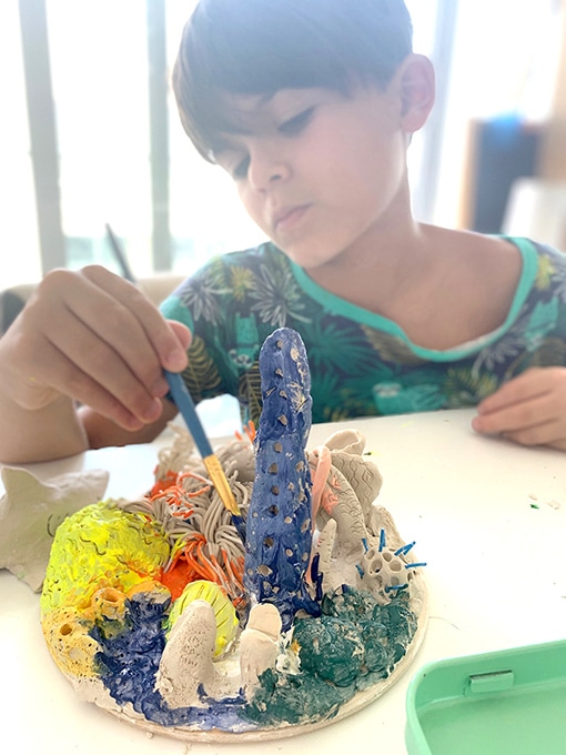 child painting clay coral sculpture